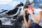 What to do after a car accident being pondered by a woman on the phone.